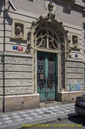 Praha /  Dvě polofigurky, které vykukují z 'oken'
